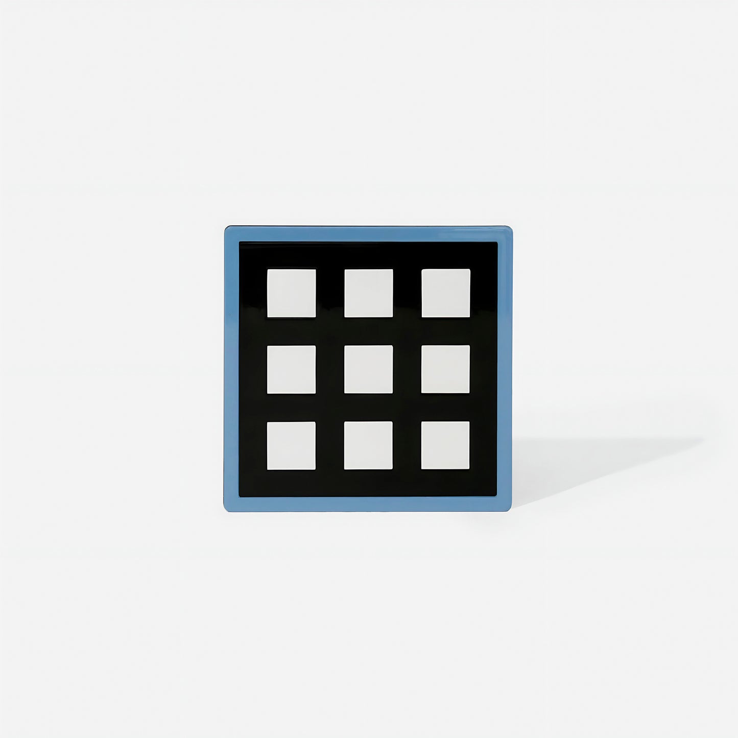Blue square metal coaster with nine white square cut-outs and glossy cobalt blue frame – handcrafted by ISUWA for bold and balanced table styling