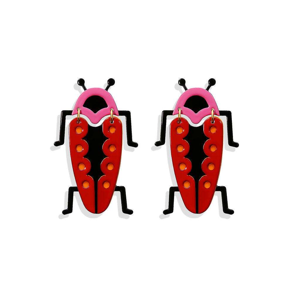 Sculptural red bug-shaped earrings with pink detailing, black legs and yellow dots, designed by ISUWA and photographed on a white background.
