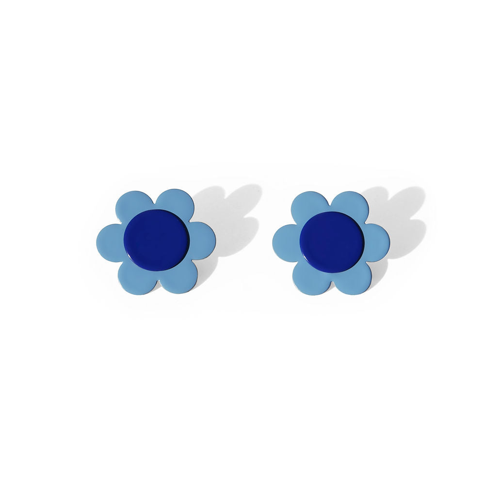 Pair of small daisy earrings with light blue petals and dark blue centers, displayed on a white background with soft shadows.
