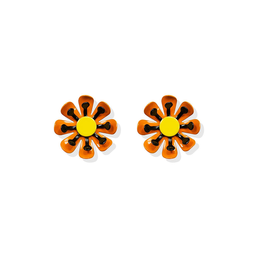 Sculptural daisy-shaped earrings with orange open petals and a yellow center with black detailing, designed by ISUWA and photographed on a white background.

