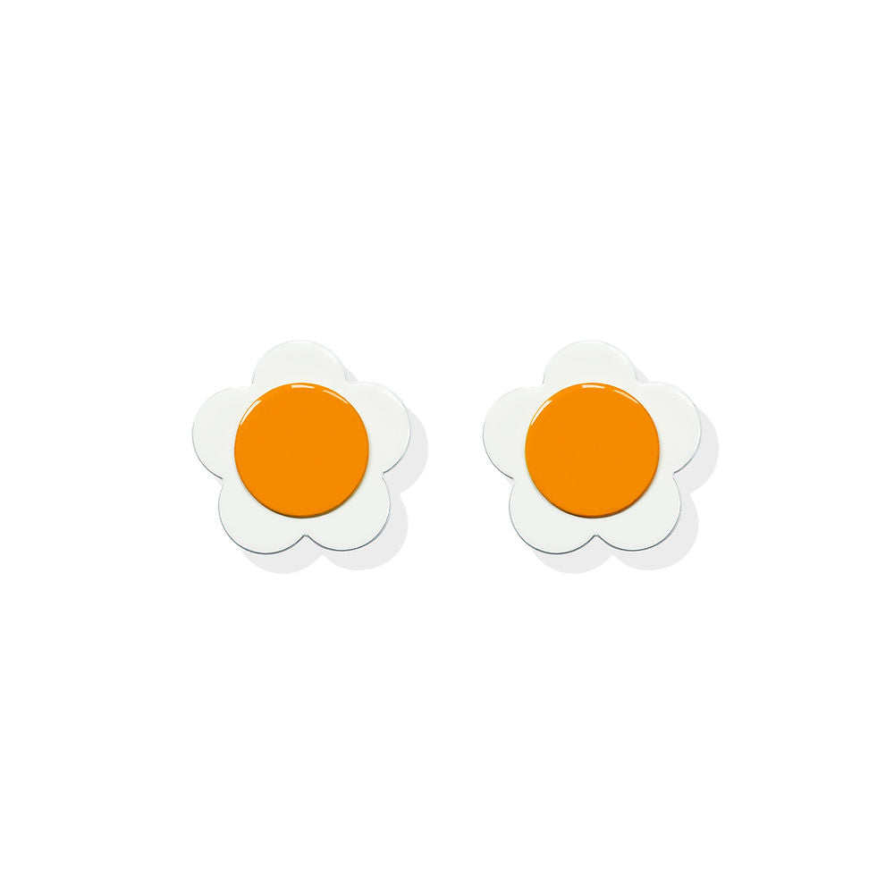 White flower-shaped earrings with bold orange centers in a sculptural design by ISUWA, photographed on a white background.
