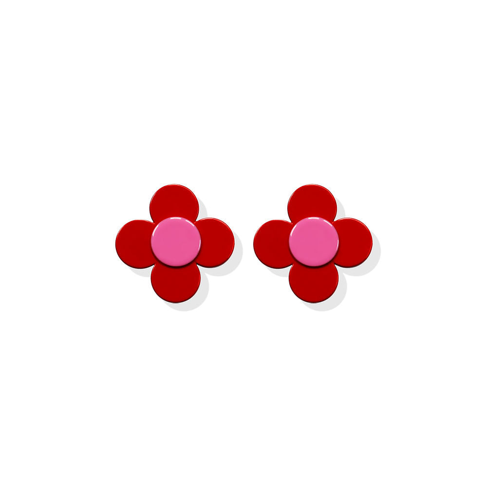 Small red flower-shaped earrings with a pink center in a sculptural design by ISUWA, photographed on a white background.
