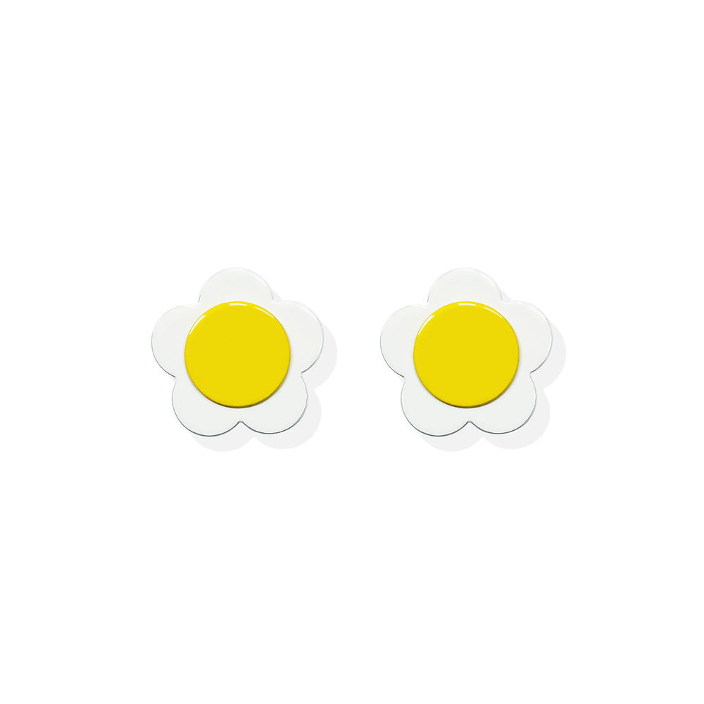 White flower-shaped earrings with a bright yellow center in a sculptural design by ISUWA, photographed on a white background.
