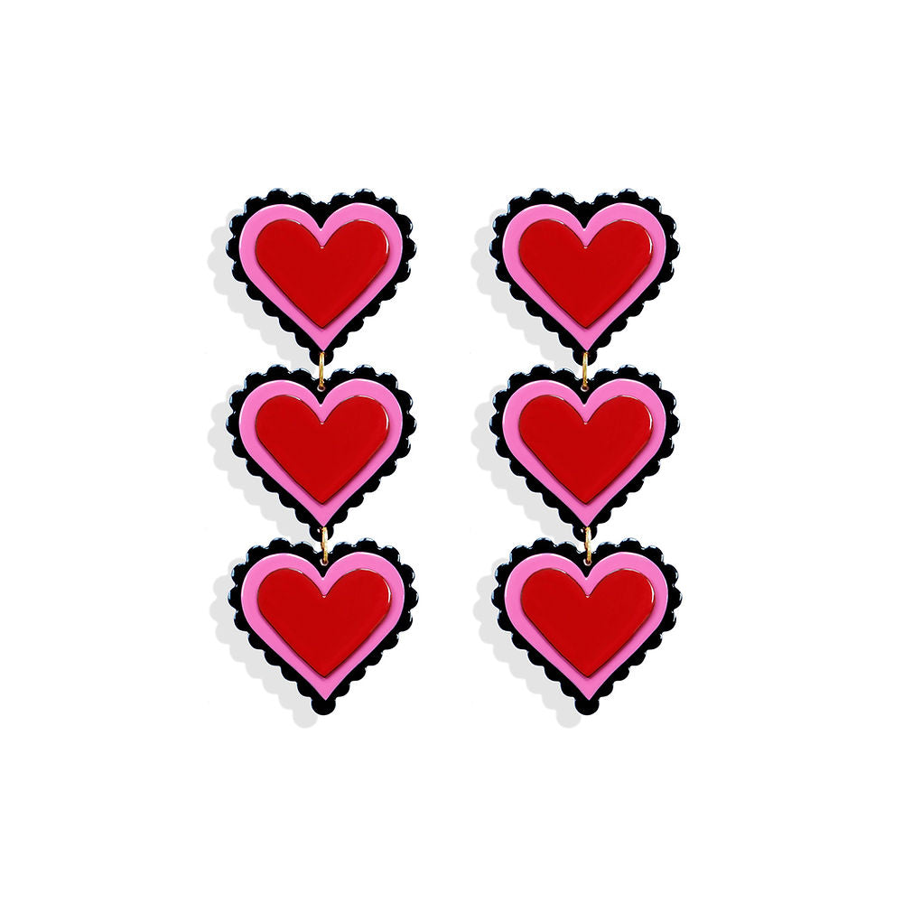 Long sculptural earrings featuring three stacked red hearts with pink and black scalloped edges, designed by ISUWA and photographed on a white background.
