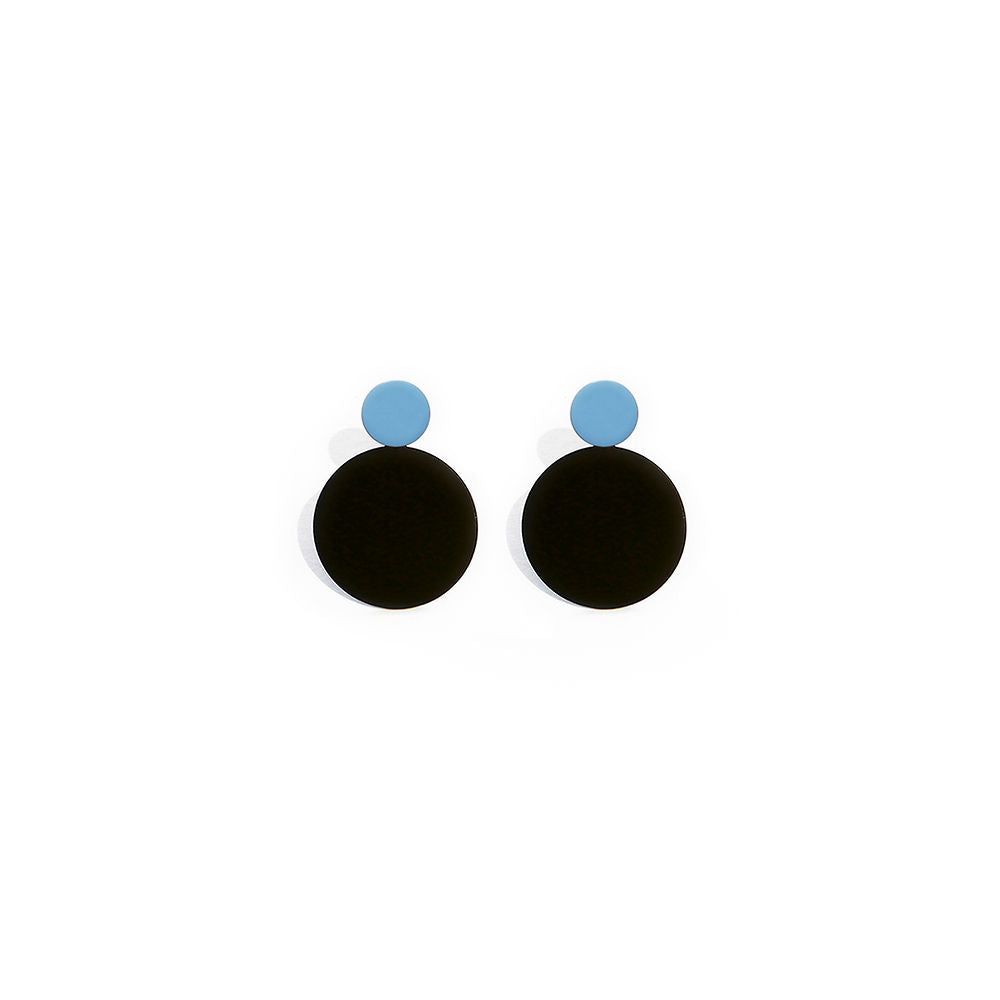 A pair of sculptural earrings with glossy black circular bases and soft blue studs. Minimal and bold design, displayed on a clean white background.
