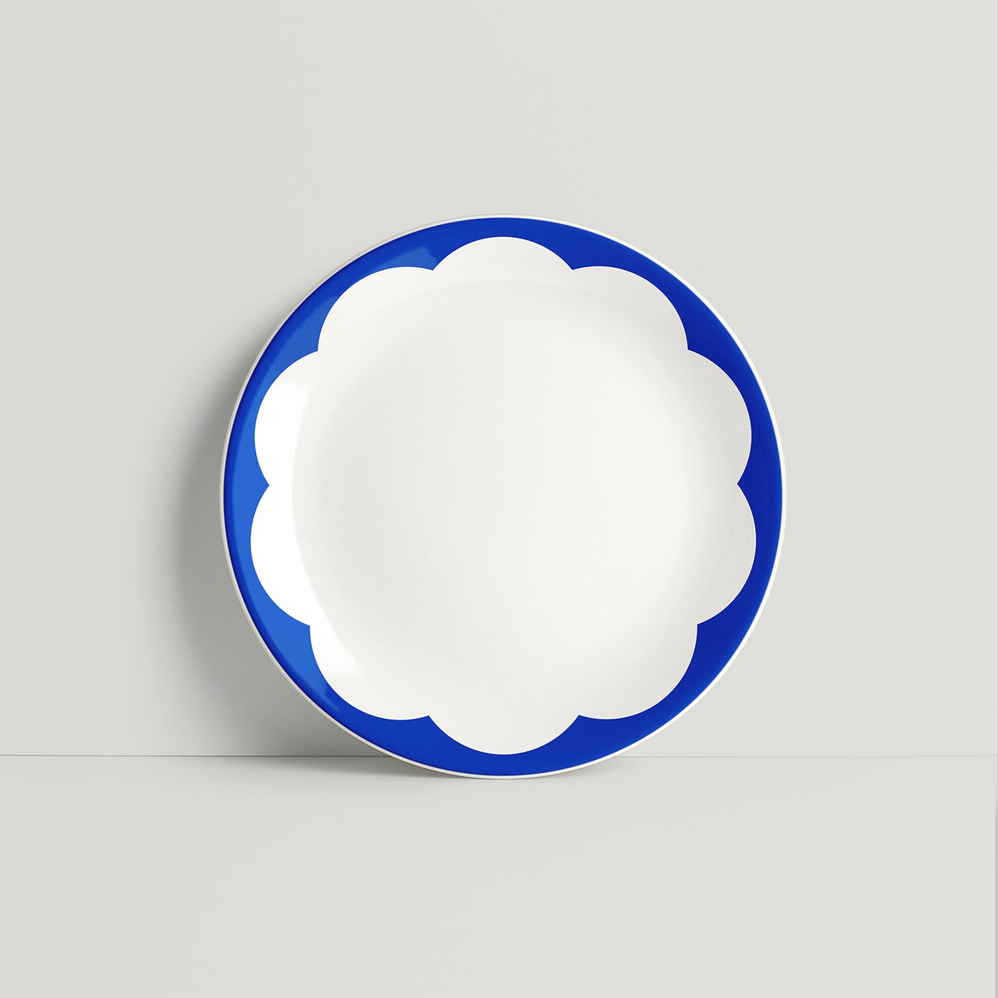 ISUWA glazed porcelain plate in vivid blue with large petal-shaped edges forming a stylized daisy pattern
