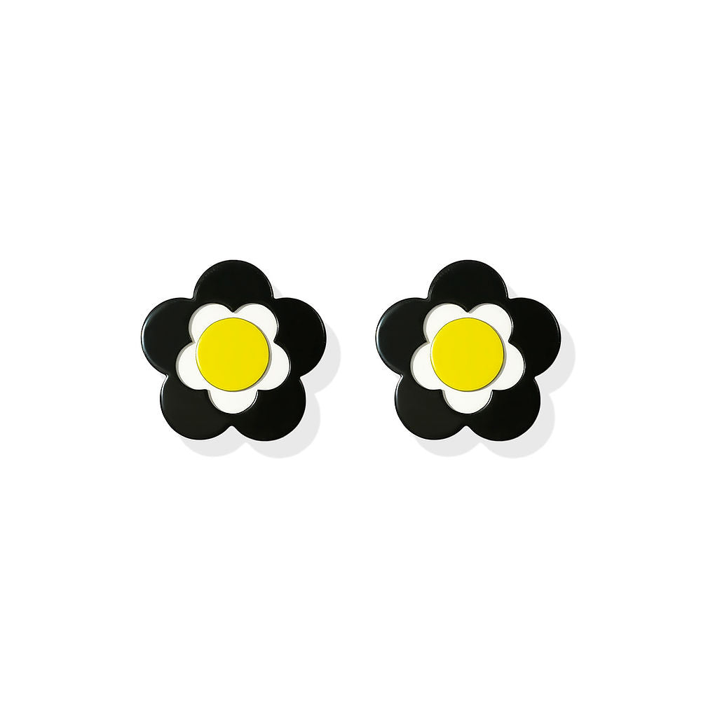 Flower-shaped earrings with black petals, white inner bloom and yellow center, designed by ISUWA and photographed on a white background.
