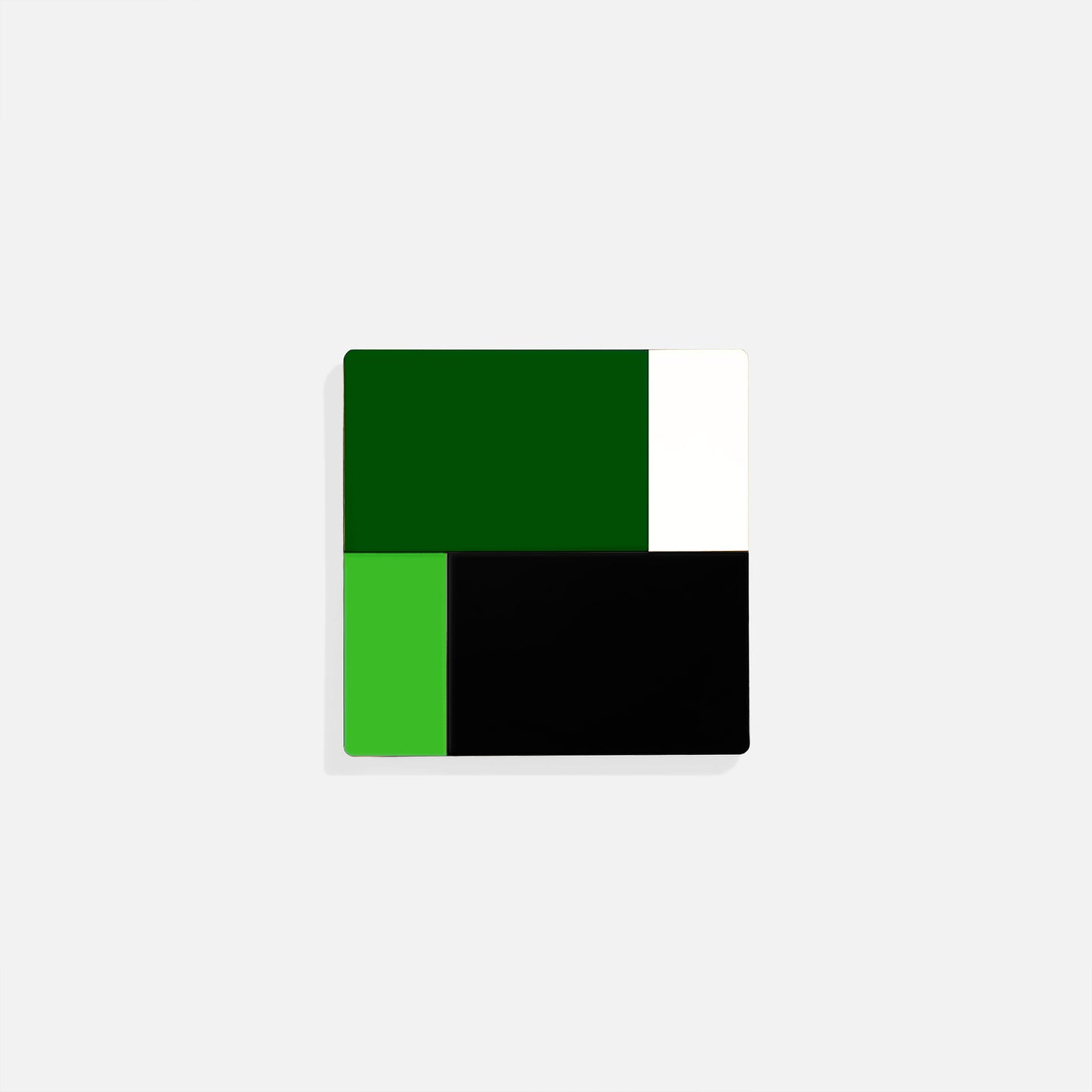 Green square metal coaster with deep forest and lime green color blocks framed by black and white – handcrafted by ISUWA for bold and graphic table styling