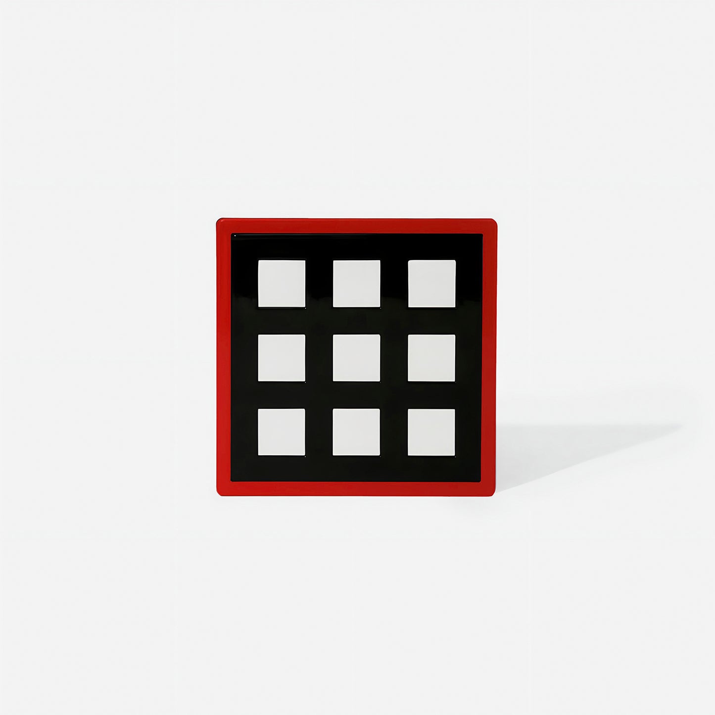 Red square metal coaster with nine white square cut-outs and glossy finish – handcrafted by ISUWA for bold and expressive table styling