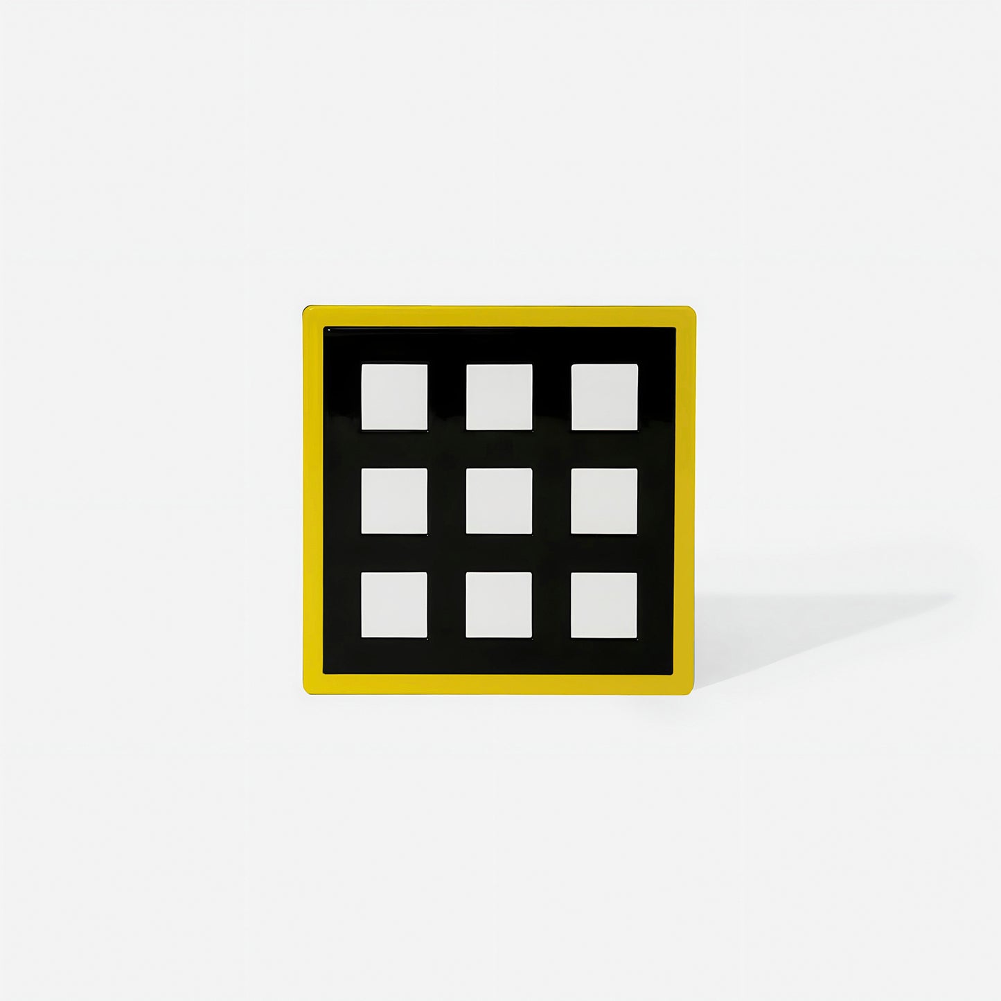 Yellow square metal coaster with nine white square cut-outs and glossy finish – handcrafted by ISUWA for bold and joyful modern table settings