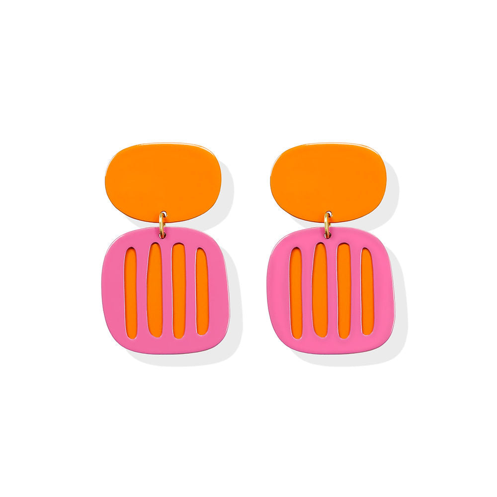 Sculptural pink earrings with vertical orange stripe cutouts and a bold orange top, designed by ISUWA and photographed on a white background.
