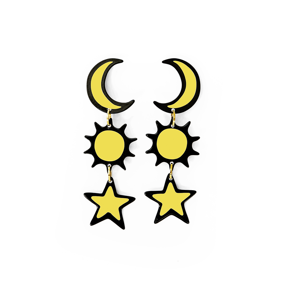 Pair of yellow earrings featuring crescent moons, suns, and stars in a playful celestial arrangement, displayed on a grey background.
