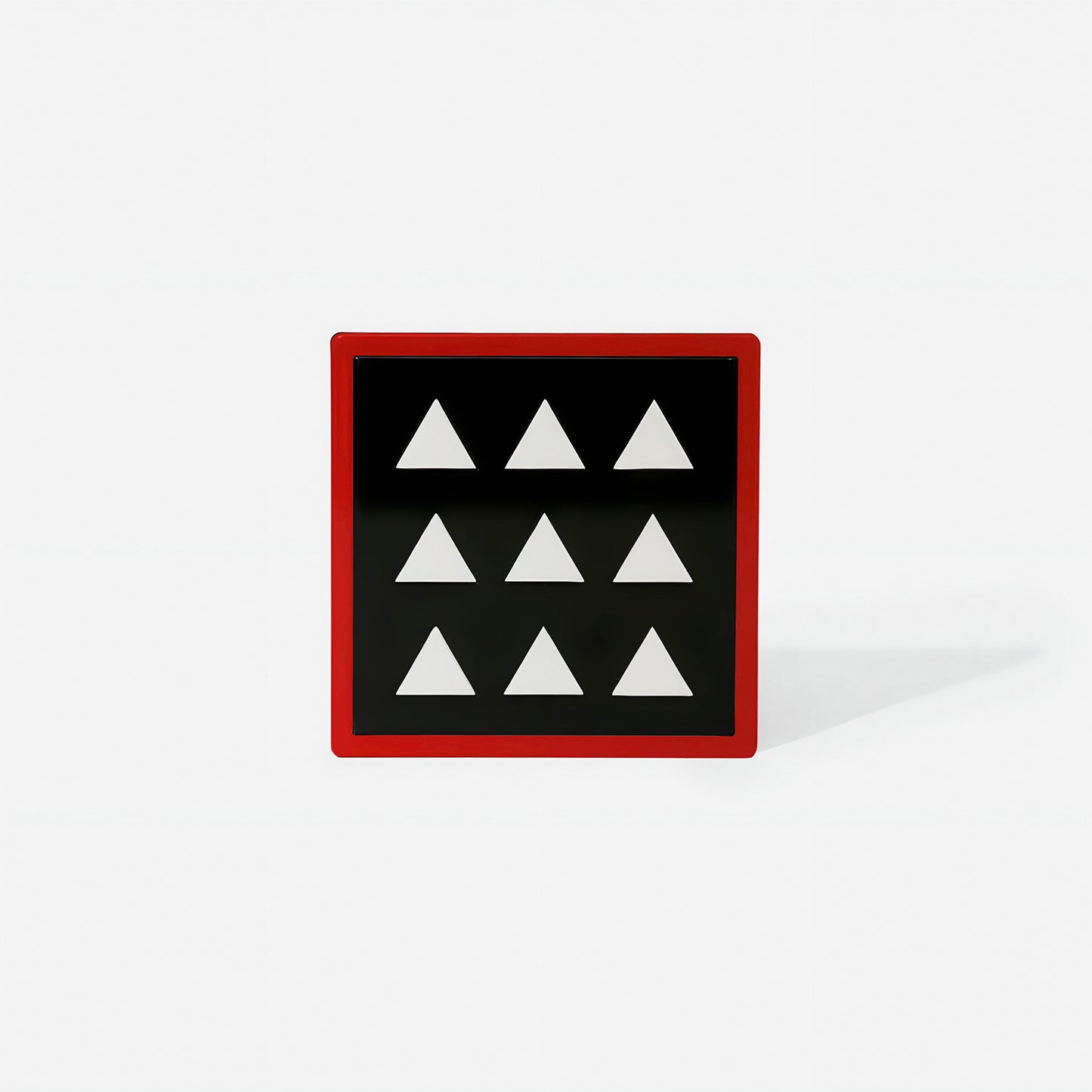 Red square metal coaster with nine white triangle cut-outs and glossy finish – handcrafted by ISUWA for bold and geometric table styling