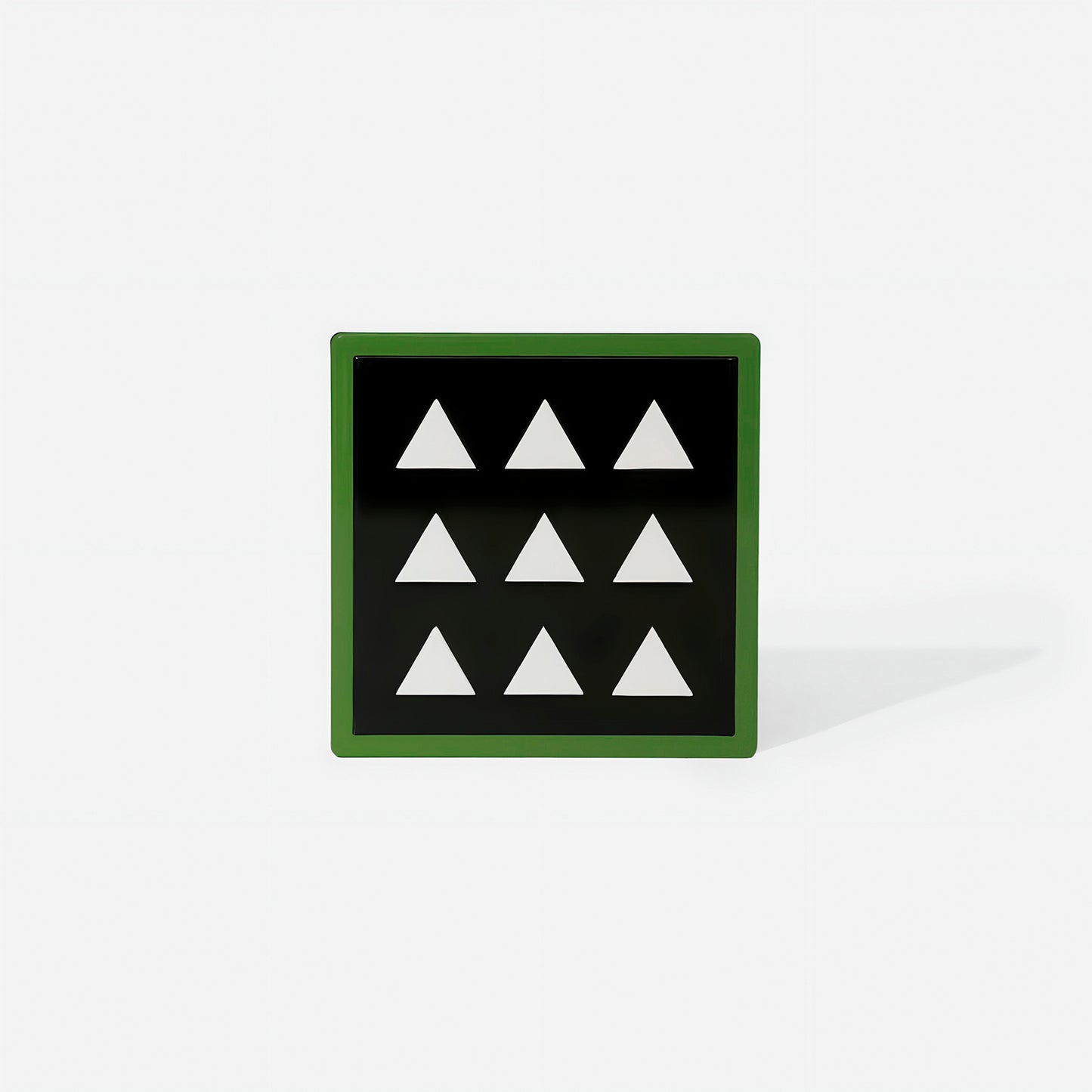 Green square metal coaster with nine white triangle cut-outs and glossy green frame – handcrafted by ISUWA for modern and graphic table styling