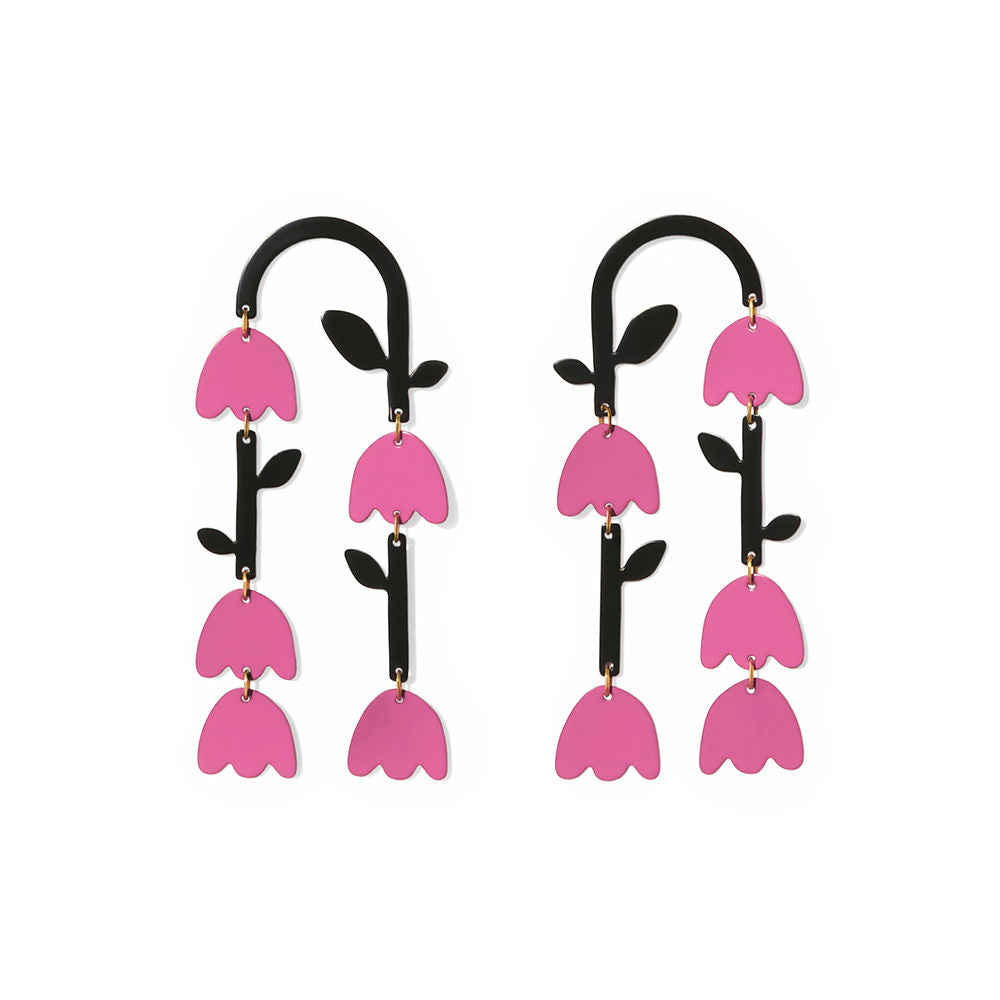 Pair of pink tulip-shaped statement earrings with layered petals and black curved tops, displayed on a white background – bold and sculptural design by ISUWA.
